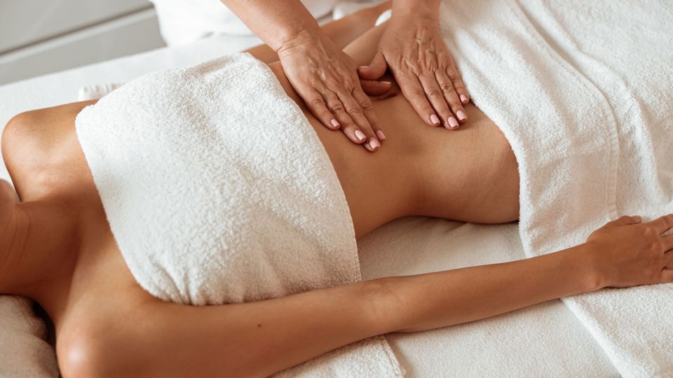 Female client receiving stomach massage in spa salon