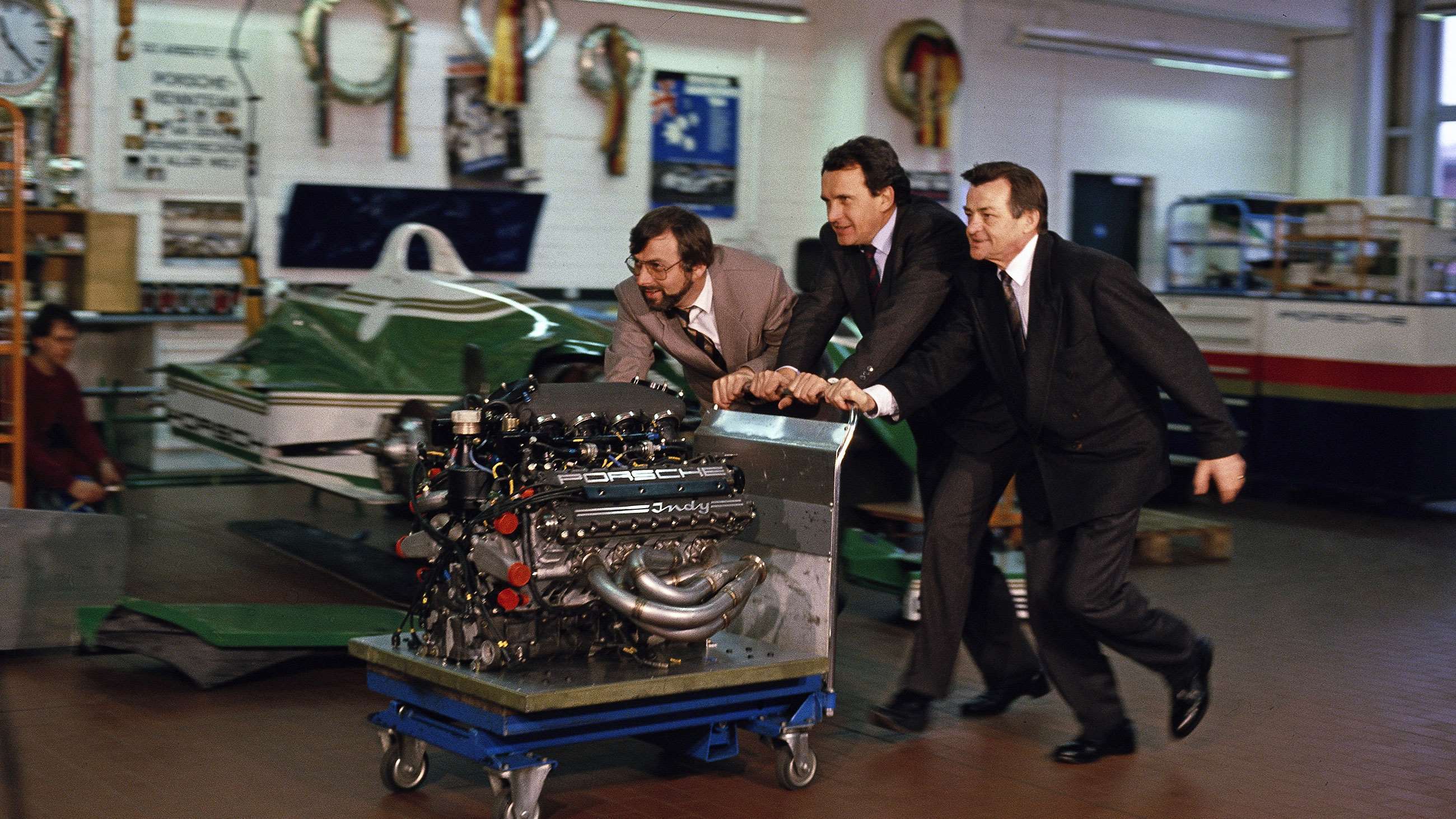 1990. Mezger (right) with Porsche project manager Helmut Flegl (centre) and engineer Hans Joachim Esch (left) pushing the 2.6-litre, turbocharged V8 Type 2708 engine across the workshop floor at great pace!
