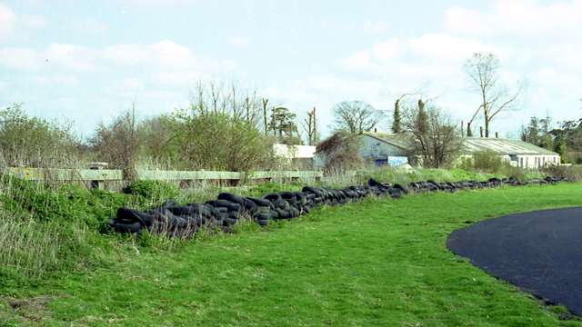 Woodcote Corner entry - the tyre and earth bank barrier perhaps unconvincing - with the Shell Building amongst the shrubbery beyond there…