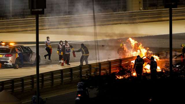 Having escaped the fire, marshals attempt to put out the flaming Haas VF-20 safety cell. The barrier had no tyres surrounding it, allowing Grosjean's car to split the barrier in two.